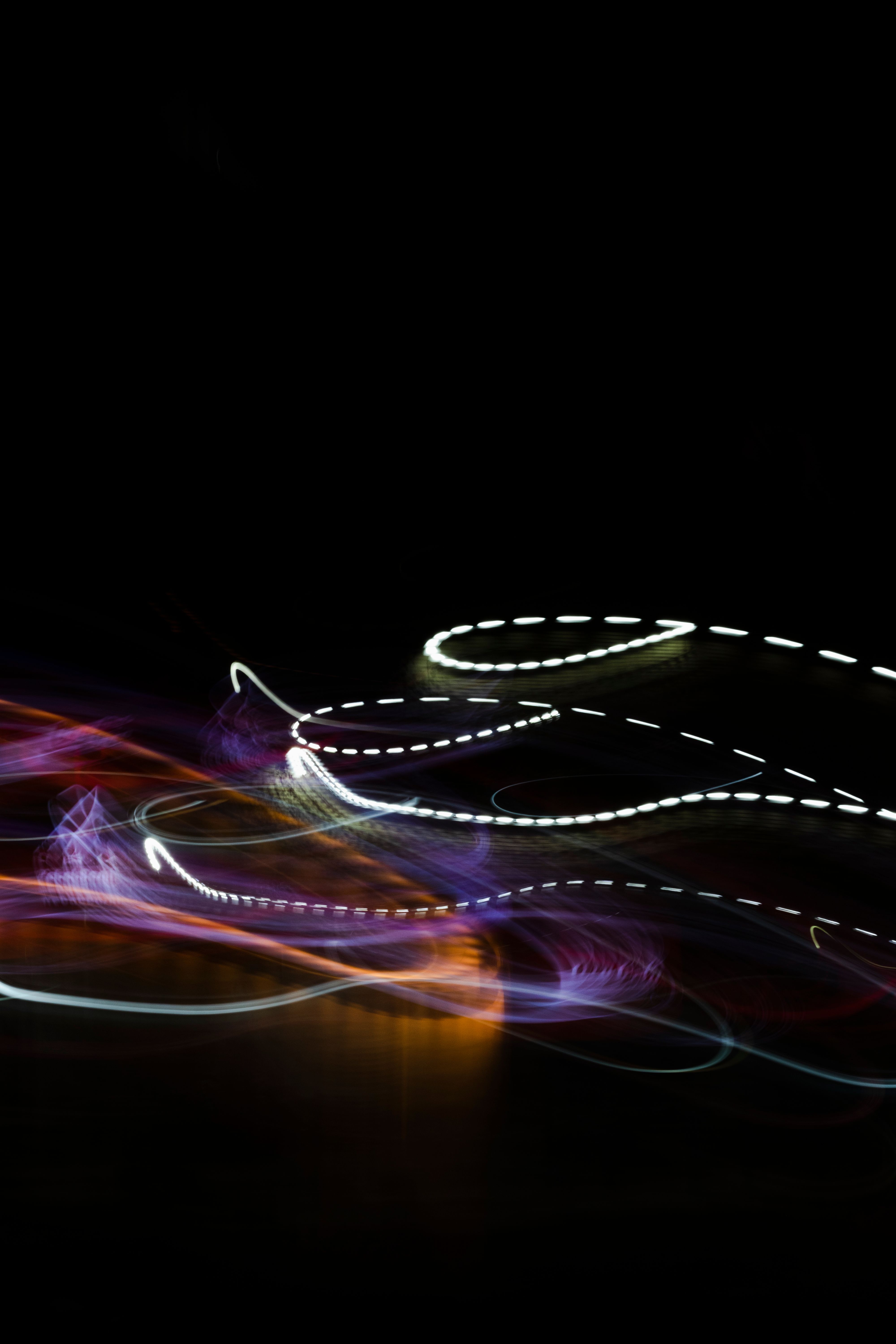 Rainbow light trails looping through darkness.