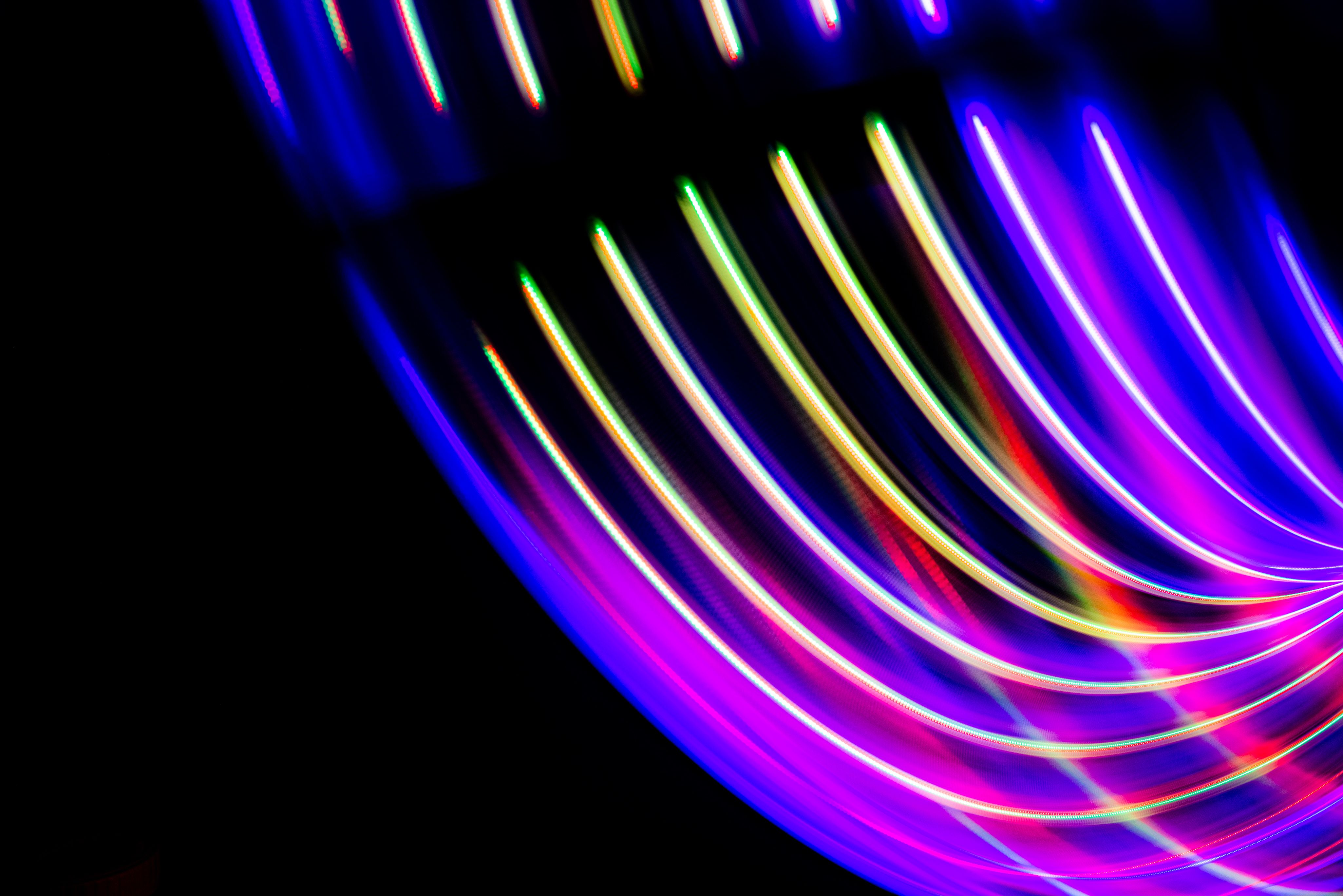 Warm neon light trails sweeping across a dark frame.