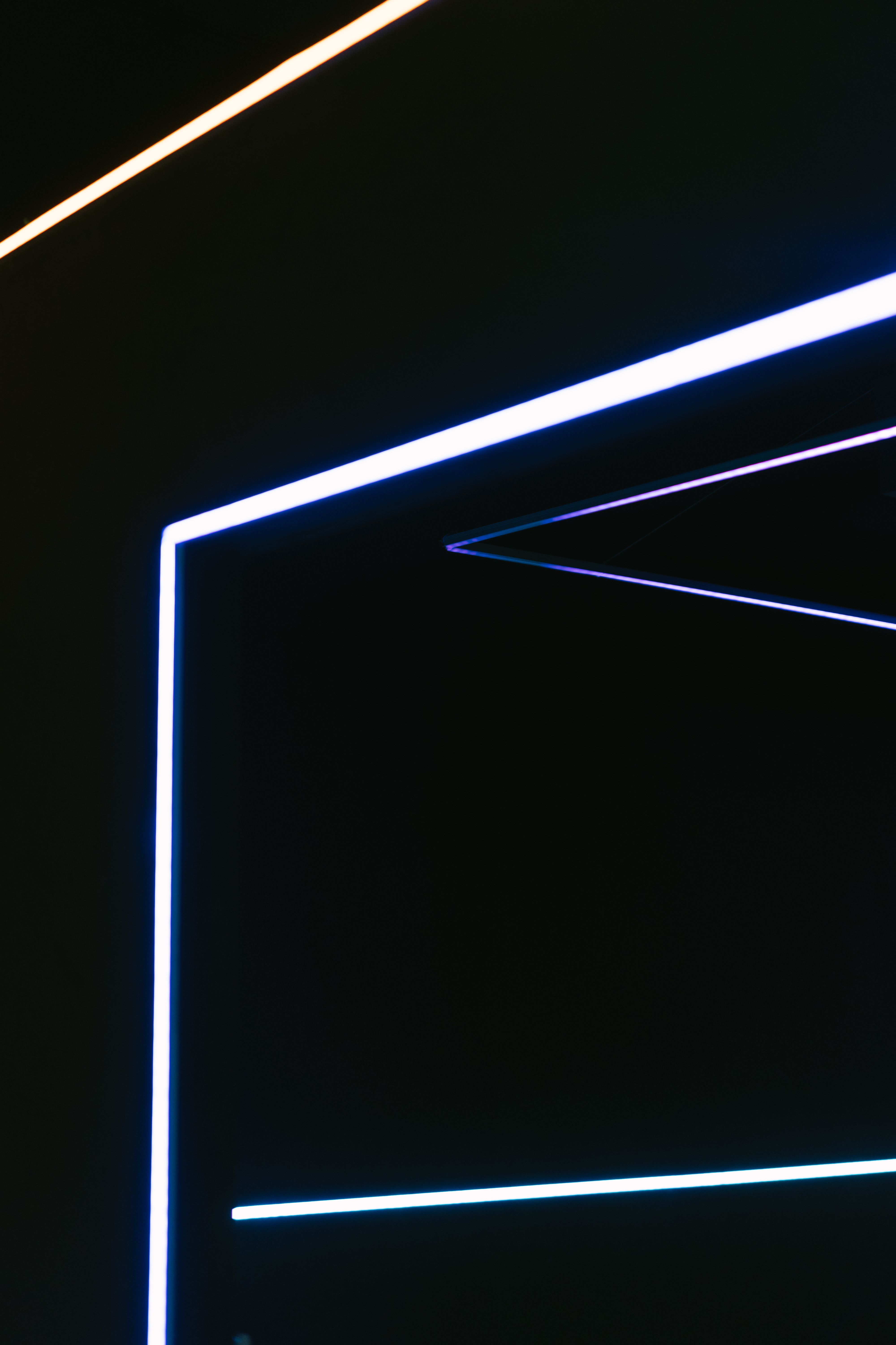 Geometric shapes drawn with neon strip lights in a dark room.